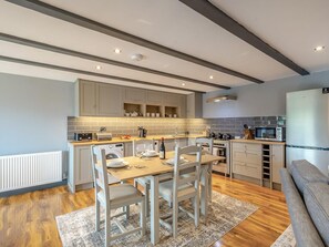 A modern kitchen with a dining area, wooden flooring, and built-in appliances. - 2 Bed in Otley (oc-96431) (Norwood)