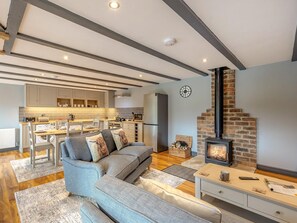 A modern living room with a sofa, a fireplace, and a kitchen in the background.