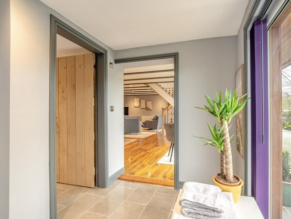 A hallway leading to a living area with a staircase, wooden flooring, and a potted plant.
