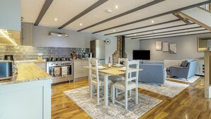 Une cuisine moderne avec un coin repas, un plancher en bois et un téléviseur dans le salon.