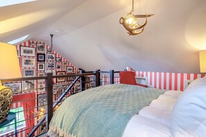 A bedroom with a sloped ceiling, a bed with a patterned blanket, a hanging light fixture, and a staircase with striped railings. - 1 Bed in Eye- (oc-34390) (Stoke Ash)