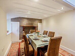 Ein Essbereich mit Backsteinwand, Holzbalkendecke und einem Tisch für vier Personen.