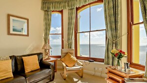A living room with a sofa, armchair, and a table with a vase of flowers. - 2 Bed in Tenby (oc-fb232) (Tenby)