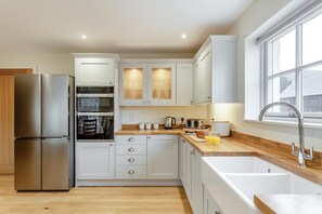 A modern kitchen with stainless steel appliances, white cabinetry, and a wooden countertop. - 3 Bed in Lairg (oc-96459) (Achfary)