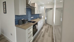 A modern kitchen with white cabinets, a blue backsplash, and a wooden countertop. - 1 Bed in Isle Of Arran (oc-96463) (Machrie)