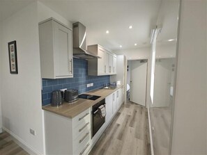 A modern kitchen with white cabinets, a blue backsplash, and a wooden countertop. - 1 Bed in Isle Of Arran (oc-96463) (Machrie)