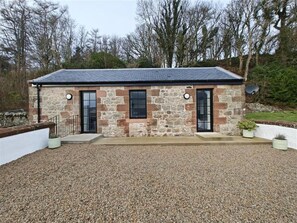 A stone building with a gravel driveway, two doors, and a satellite dish. - 1 Bed in Isle Of Arran (oc-96463) (Machrie)