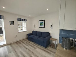 A modern living room with a sofa, a small table, a kettle, and a window with curtains. - 1 Bed in Isle Of Arran (oc-96463) (Machrie)