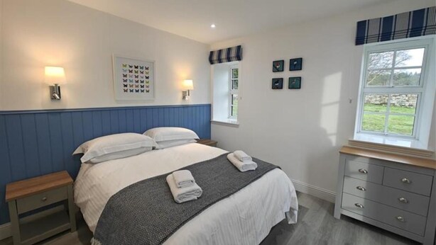 A bedroom with a bed, bedside tables, a dresser, wall art, and a window. - 1 Bed in Isle Of Arran (oc-96463) (Machrie)