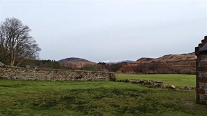 A stone wall, a grassy field, and a mountain in the background. - 1 Bed in Isle Of Arran (oc-96463) (Machrie)