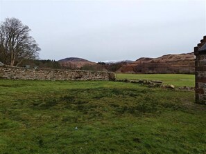 A stone wall, a grassy field, and a mountain in the background. - 1 Bed in Isle Of Arran (oc-96463) (Machrie)