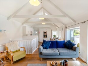 A spacious living area with a sofa, a dining table, and a kitchen in the background. - 2 Bed in Cardigan (oc-41684) (Tresaith)