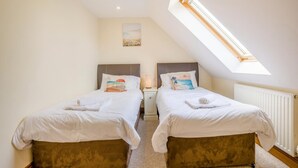 A bedroom with two beds, a skylight, a painting, and a radiator. - 5 Bed in Bridport (oc-bigov) (Charmouth)