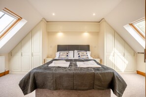 Une chambre à coucher avec un grand lit, deux tables de chevet, une tête de lit et un puits de lumière.