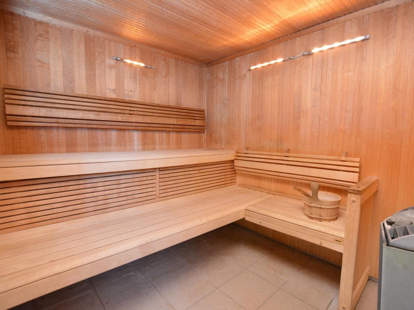 A wooden sauna with benches and a wooden bucket.