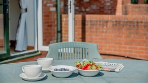 Une table sur laquelle se trouvent un bol de fraises, un bol de myrtilles et deux tasses blanches, le tout posé sur une table bleue.