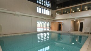 Une piscine intérieure à l’eau claire, avec des murs carrelés et un plafond haut.