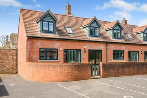 A brick building with multiple windows and a gated entrance. - 2 Bed in Bridport (oc-blueh) (Charmouth)