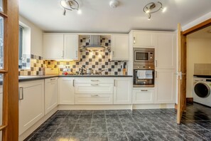Eine moderne Küche mit weißen Schränken, einer gefliesten Spritzschutzwand, einem eingebauten Backofen und einer Waschmaschine.