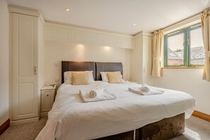 A hotel room with a large bed, a nightstand, a wardrobe, and a window with curtains. - 4 Bed in Bridport (oc-charv) (Charmouth)