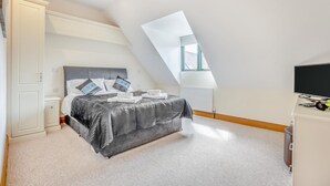 Un dormitorio con cama, escritorio, silla, televisor y ventana.