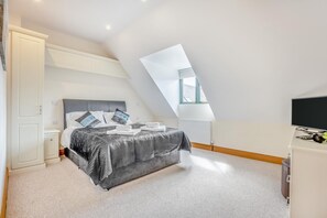 Ein Schlafzimmer mit einem Bett, einem Schreibtisch, einem Sessel, einem Fernseher und einem Fenster.