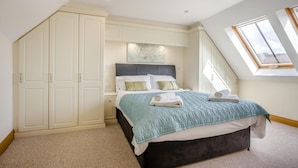 Een slaapkamer met een bed, een kledingkast, een dakraam en een schilderij aan de muur.