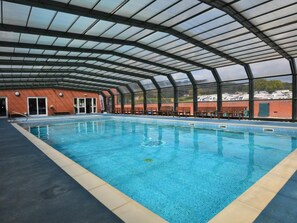 An indoor swimming pool with a glass ceiling, a brick wall, and a view of boats outside. - 2 Bed in Bridport (oc-regis) (Charmouth)