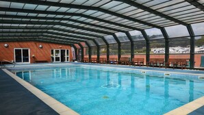 An indoor swimming pool with a glass ceiling, a brick wall, and a view of boats outside. - 2 Bed in Bridport (oc-restw) (Charmouth)