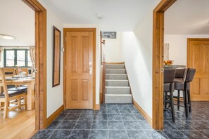 Ein Flur mit einer Holztür, einer Treppe und einem Essbereich mit Stühlen und einem Tisch.