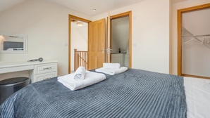 A bedroom with a bed, a desk, a mirror, and a wardrobe. - 3 Bed in Bridport (oc-tcsaila) (Charmouth)
