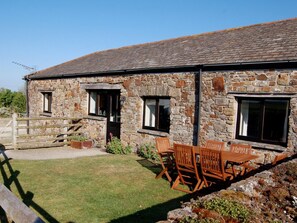 A stone building with a wooden table and chairs outside. - 2 Bed in Widemouth Bay  (4727) (Poundstock)