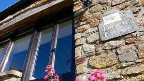 Ein Steinhaus mit einem Schild, auf dem 'Cottons Cottage' steht.