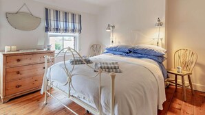 Ett sovrum med en säng, byrå, sänglampor och en stol.