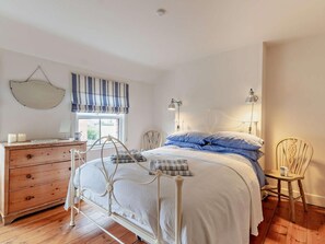 Ein Schlafzimmer mit einem Bett, einem Schminktisch, Nachttischlampen und einem Sessel.