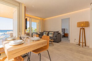 Un salon moderne comprenant un coin repas, un ensemble de canapés et une vue sur la mer.