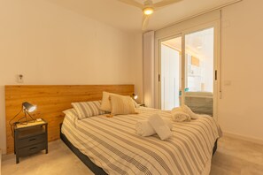 A bedroom with a wooden headboard, a bed with striped bedding, a nightstand with a lamp, and a sliding glass door leading to an outdoor area. - 1 Yacht Club with ocean views and parking (Calp)