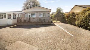 Une résidence mobile de type caravane, dotée d’une cour avant clôturée et d’une allée gravillonnée.