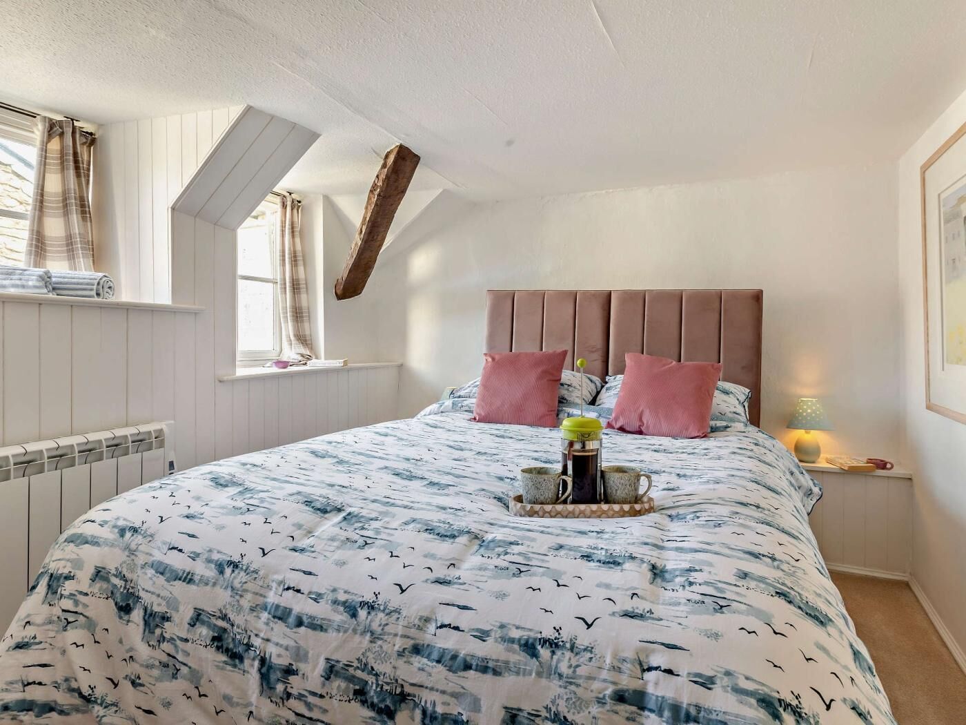 Une chambre à coucher avec un lit, une fenêtre, un radiateur et une table de chevet avec une lampe.