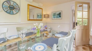A dining room with a glass table, white chairs, and a vase of flowers. - 3 Bed in Ambleside (oc-96511) (Claife)