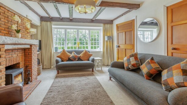 A cozy living room with a fireplace, a sofa, and a window with curtains. - 3 Bed in Ambleside (oc-96511) (Claife)