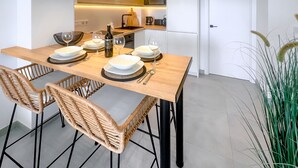 Une cuisine moderne avec une table à manger pour quatre personnes, comprenant un îlot central doté d’un évier et d’un micro-ondes installé au-dessus.