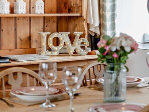 A wooden dining table with plates, glasses, and a 'LOVE' sign. - 2 Bed in Bude (oc-04727) (Poundstock)