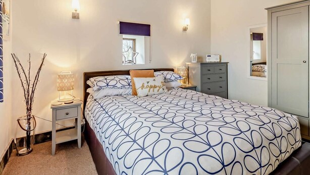 A bedroom with a bed, bedside tables, a dresser, a mirror, and a window. - 2 Bed in Bude (oc-04727) (Poundstock)