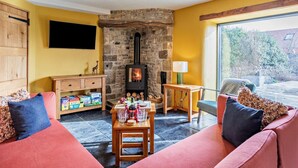 Una sala de estar acogedora con chimenea de piedra, televisor y sofá con cojines.