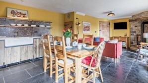 Un comedor con mesa y sillas de madera, una cocina con encimera de mármol y una chimenea de piedra.