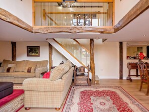 A spacious living area with a high ceiling, a staircase, and a dining area with a wooden table and chairs. - 2 Bed in Thetford (oc-57885) (Saham Toney)