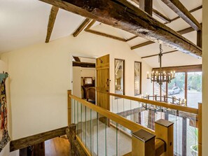 Un escalier en bois avec une rampe en verre menant à une pièce ornée d’un lustre.