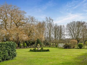 A well-maintained garden with a variety of trees, a neatly trimmed lawn, and a central circular flower bed. - 2 Bed in Thetford (oc-57885) (Saham Toney)