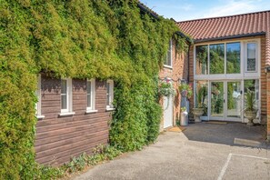 A house with a brick exterior, a wooden front porch, and a large glass door entrance. - 2 Bed in Thetford (oc-57885) (Saham Toney)